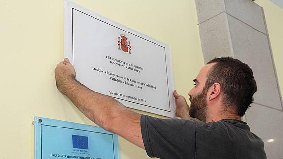 Un operario coloca la placa corregida en la Estación de Palencia.