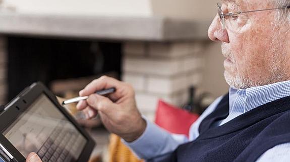 Un hombre utuiliza una tableta en su casa.