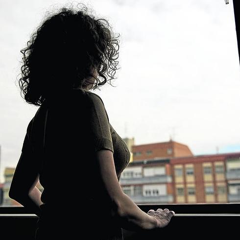 Una mujer maltratada, que quiere mantener el anonimato, se asoma a una ventana en un piso. 