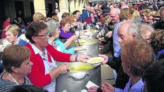 Las amas de casa reparten las raciones de patatas con bacalao preparadas para 700 comensales. 