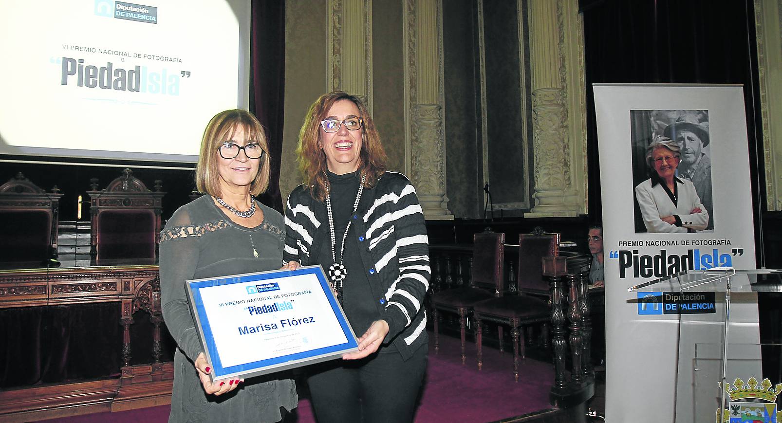 Marisa Flórez, a la izquierda, posa con el diploma que acredita el Premio Piedad Isla, junto a la presidenta de la Diputación.