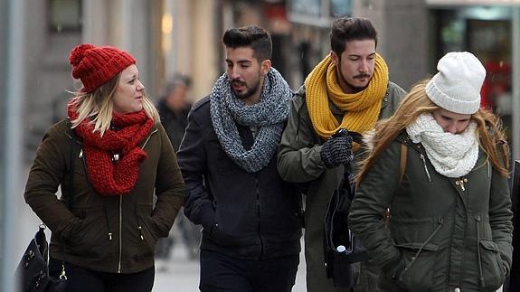 Varios jóvenes soportan la bajada de temperaturas en Segovia con abrigos, gorros y bufandas,