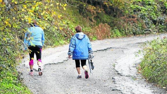 Dos mujeres caminan por la senda en la que el grupo leonés inició la ruta con quad. 