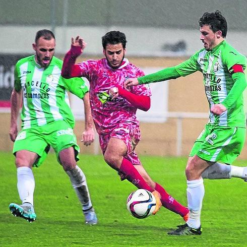 Ayub, que debutó con la camiseta del Guijuelo, rodeado de dos rivales del Somozas.