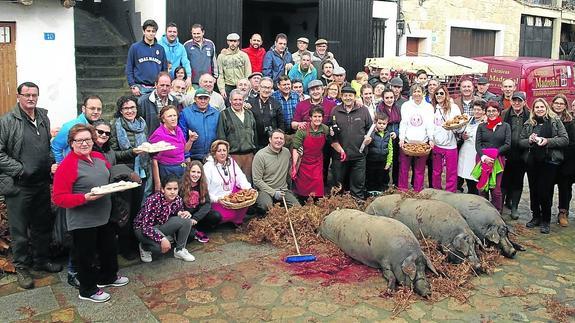 Los asistentes a la matanza organizada ayer por Cárnicas Madroñal, junto a los tres cerdos que fueron sacrificados y despiezados. 