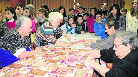 Las abuelas de la residencia enseñan el proceso del atado de los chorizos a los alumnos del colegio San Pedro.