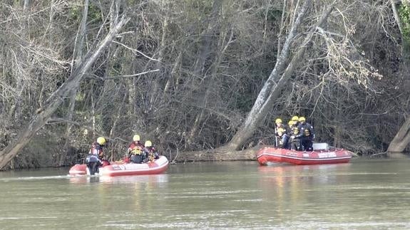 Bomberos y voluntarios de Salvamento rastrean la orilla junto al puente de Santa Teresa. 