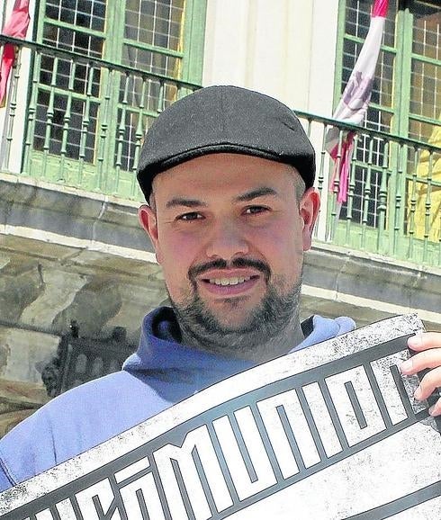 Ángel Galindo sujeta el cartel del concierto de hoy de Excómunion, ante la fachada de la Casa Consistorial de Segovia. 