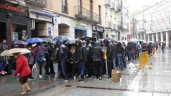 Los jóvenes aguantan la lluvia, a la puerta del estableciemiento de venta, a primera hora de la tarde. 