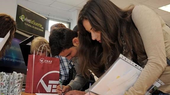 Dos universitarios entregan un currículum en un foro de empleo.