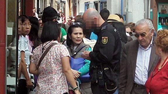 Un policía toma nota de la denuncia de unas turistas orientales, en plena Calle Real de Segovia, tras ser robadas por unos carteristas. De Torre