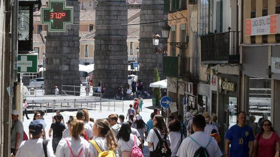 Transeúntes por la Calle Real de Segovia, este miércoles, con un termómetro que marca 37 grados. 