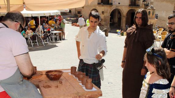 Un alfafero realiza una pieza ante la mirada de algunos participantes en la Feria de los Fueros de Sepúlveda. 