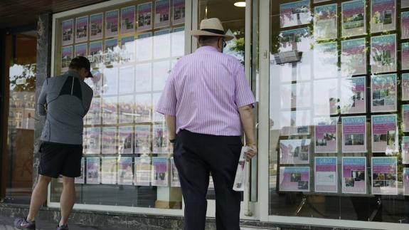 Dos ciudadanos observan las ofertas de viviendas de una inmobiliaria. /  LOBO ALTUNA
