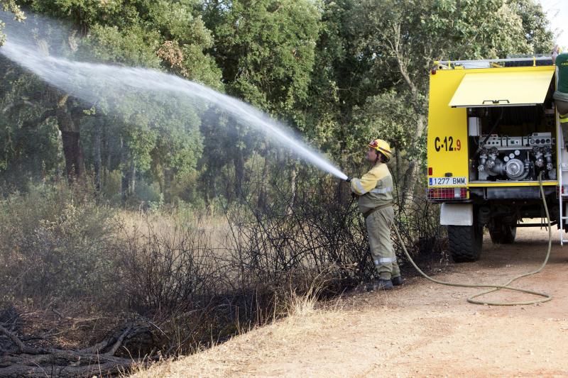 Un técnico del servicio de extinción de incendios refresca la zona donde se ha producido un incendio forestal. 