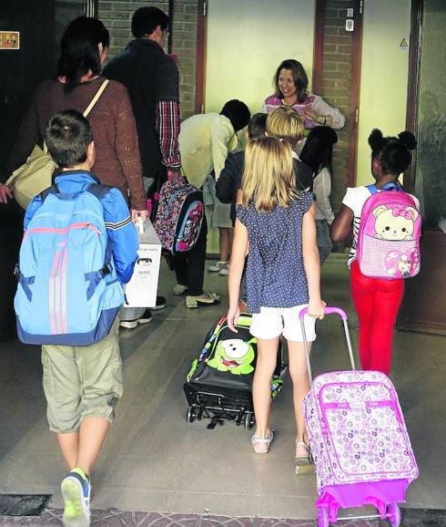 Un grupo de niños se dispone a entrar al colegio acompañados de sus padres. 