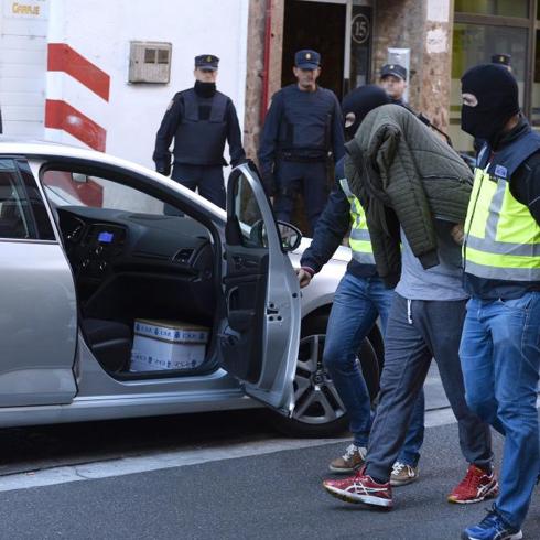 Ali, tapado con una cazadora, sale escoltado por policñias del piso que ocupara en la calle San José de Calasanz. 