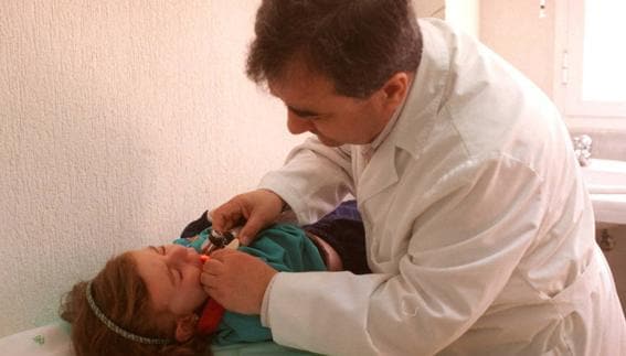 Un pediatra observa la garganta de un menor en un centro de salud 