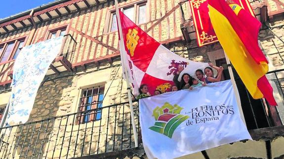 Varios niños junto a la bandera de la Asociación de los Pueblos Más Bonitos de España en Mogarraz.