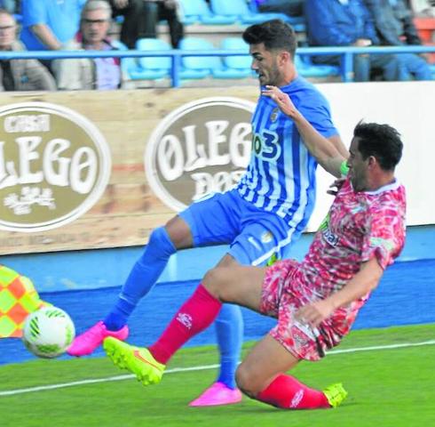 Jonathan Martín trata de recuperar un balón ante un jugador de la Ponferradina ante la mirada del asistente