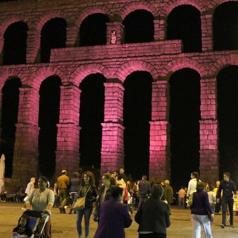 Gruppos de personas pasan y observa, en la noche del martes, el Acueducto iluminado de rosa por el Día Internacional de las Niñas. 