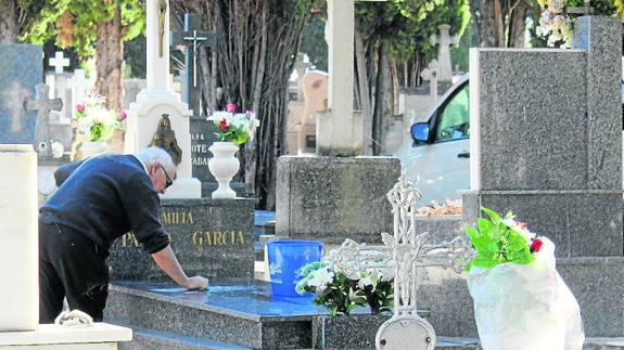 Un hombre limpia una lápida, este jueves en Palencia. 
