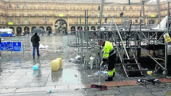 Un operario del servicio de limpieza barre en la Plaza Mayor, junto al escenario montado para la macrofiesta universitaria. 
