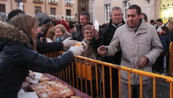 La concejala de Cultura, Carmen Fernández, sirve una porción de roscón a un palentino. 