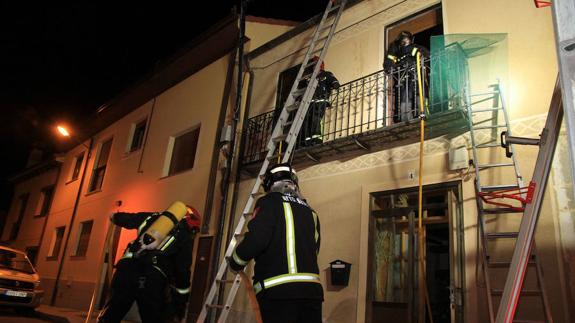 Los bomberos actúan para sofoar el incendio declarado en una vivienda de Zamarramala, este domingo por la noche. 