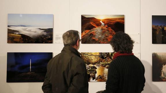Dos visitantes observan algunas de las imágenes de la muestra. 
