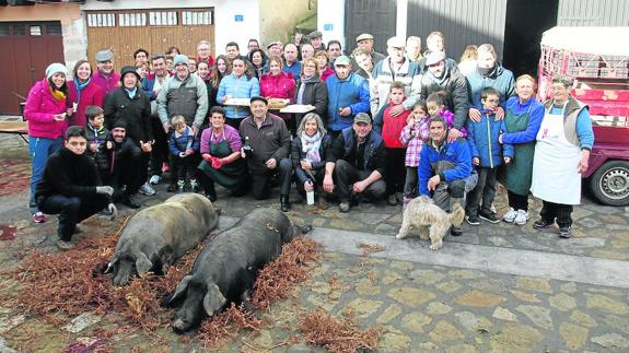 Numerosas personas asistieron a la matanza de dos cerdos en Madroñal invitados por la empresa Cárnicas Madroñal y posaron junto a los dos animales.