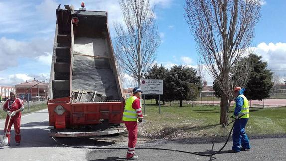 Operarios del servicio de Vías y Obras de la Diputación extienden una capa de asfalto.