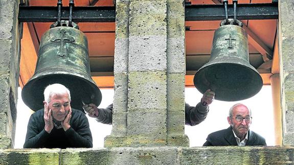 Ruidosa tradición. Dos hombres se asoman por el campanario de San Pedro de Bernueces, en Asturias, mientras tañen las campanas