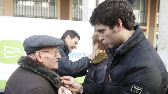 Rodrigo Mediavilla coloca una bandera de España a un vecino de Palencia en el Día de la Constitución.