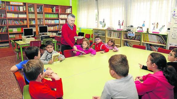 El jefe de estudios, Luis Aguado, entrega libros a los niños en la biblioteca.