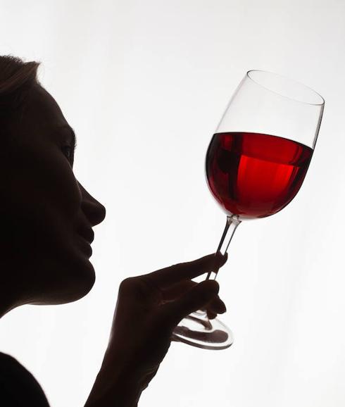 Una mujer observa una copa de vino.