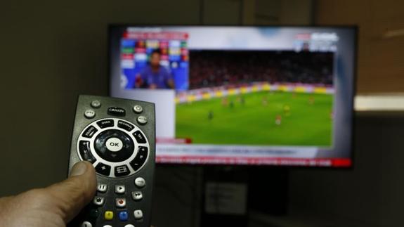 Un usuario utiliza un mando para cambiar de programa de televisión. 