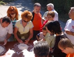 Niños y mayores observan cómo se prepara la harina. /A. SAAVEDRA