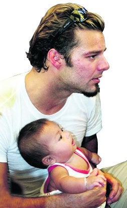 El cantante, con un bebé tailandés superviviente del tsunami del año 2004. / AFP