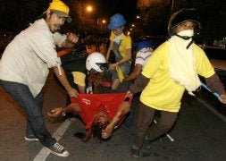 Manifestantes contra el Gobierno retiran a un herido en una calle de Bangkok. / AFP
