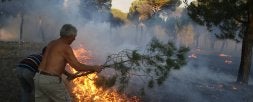 Dos vecinos  intentan sofocar las llamas con ramas en las inmediaciones del cementerio de Puente Duero, entre la carretera que une el barrio con la capital y las instalaciones de la zona de   los Pingüinos, que no se vieron afectadas./ GABRIEL VILLAMIL