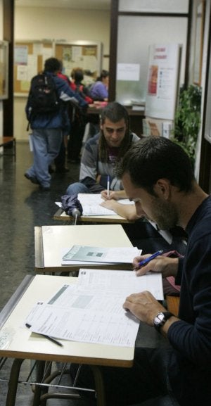 Varios alumnos rellenan los impresos de matrícula y guardan cola  en la ventanilla de información de la UNED. /FOTOS DE J. RUIZ