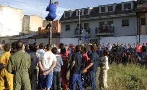 Uno de los jóvenes participantes en la cucaña trepa por el palo ayer, en el barrio de Pinilla.  ::
R.CASADO