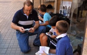 Un padre y varios niños disfrutan, ayer, intercambiando cromos en la calle. ::
JAVIER SEGOVIA