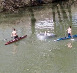 Primeras pruebas del géiser del Pisuerga, ayer al mediodía. A la derecha, dos piragüistas observan la base apagada. ::                             J. S.