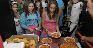 Vecinas del barrio de Nueva Segovia recogen sus raciones de macarrones, ayer, en la comida popular.  ::
A. DE TORRE