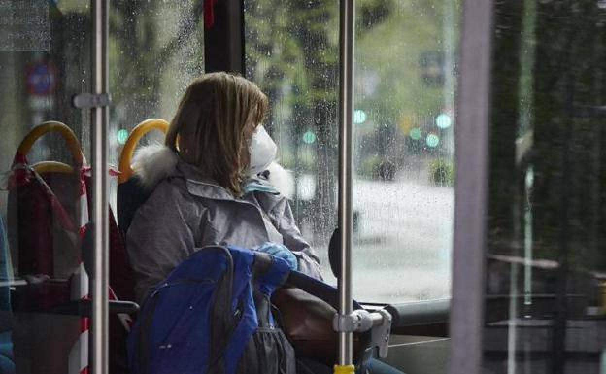 Una mujer con mascarilla en un autobús urbano. 