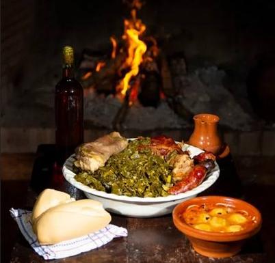 Coles con Buche, vino casero, escabechera en cuenco de barro y jarra de la alfarería local, junto al fuego. 