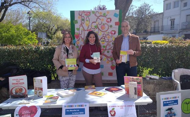 Imagen principal - La concejala Mercedes Pérez, la responsable de la biblioteca Esther Cordero y el alcalde Arroyo Carlos Caro en el fondo bibliográfico del Día de la Salud. 