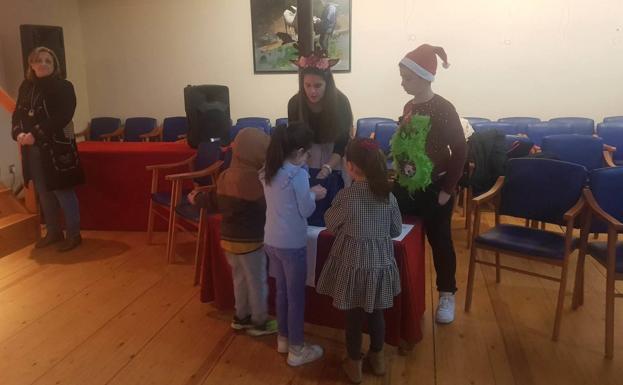 Imagen principal - Arriba, los elfos de Papá Noel repartiendo caramelos a los niños. Debajo, una niña entrega su carta en el buzón. 